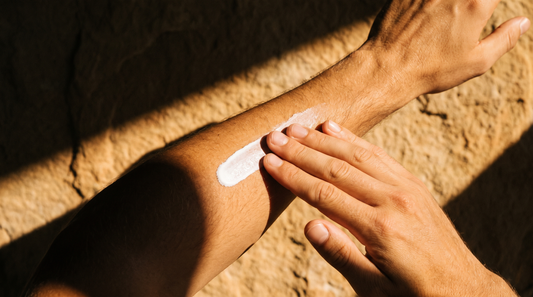 Rubbing a stripe of white sunscreen into a forearm in hard summer sunlight