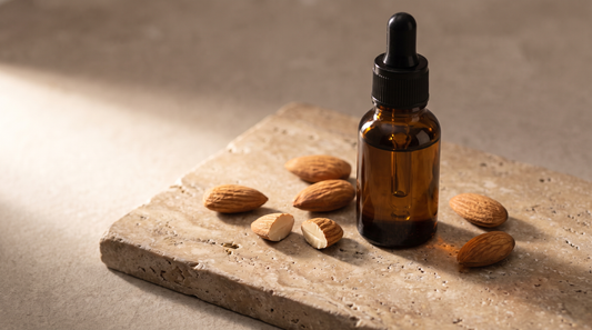 Amber glass dropper bottle on stone surrounded by raw almonds