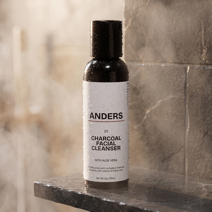 ANDERS Charcoal Facial Cleanser on a wet slate shower shelf with water droplets and steam